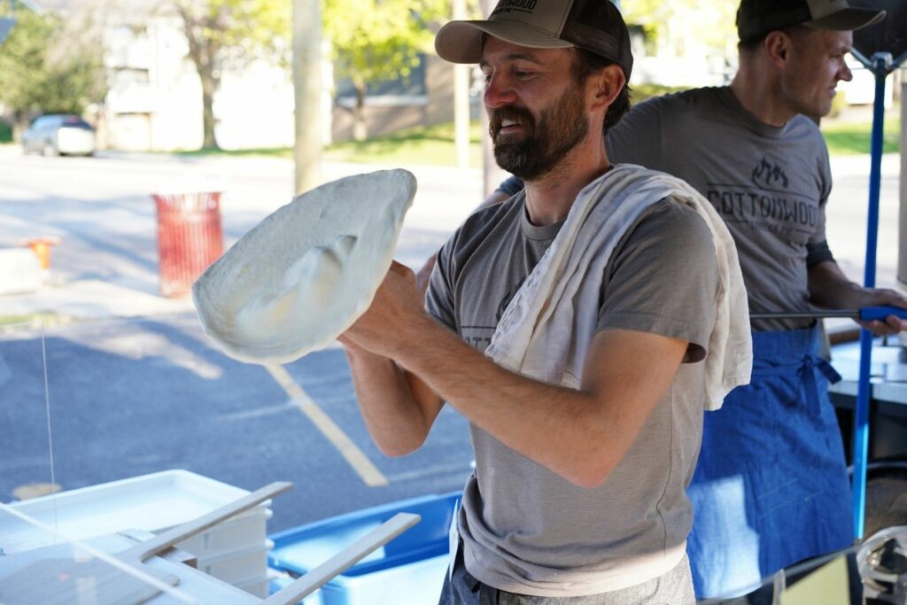 Max makes pizza for an Acts Housing event